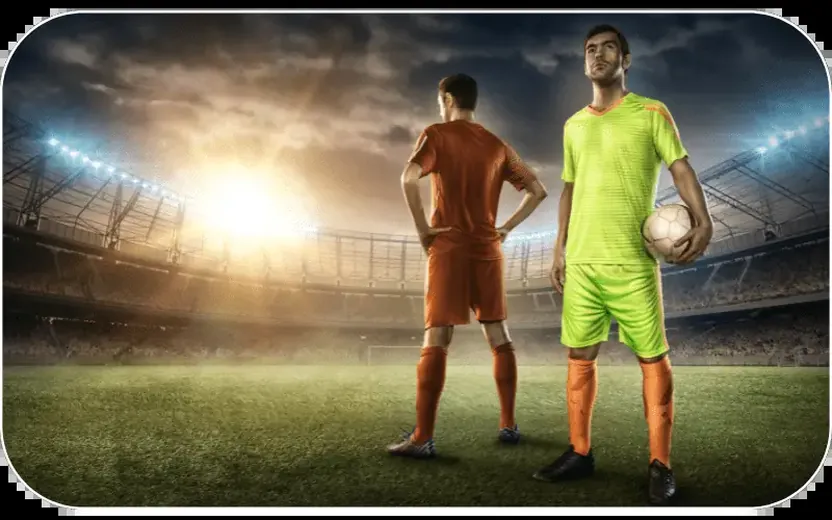 Two footballers facing off under floodlights on a night pitch